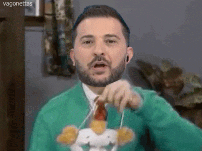 a man with a beard is wearing a green sweater and tie and holding a stuffed chicken .