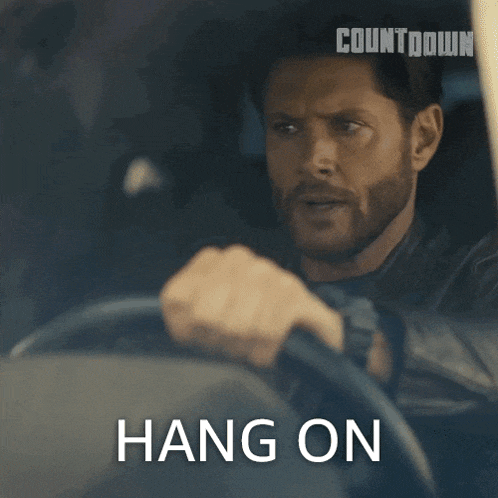 a man is driving a car with the words hang on written above him