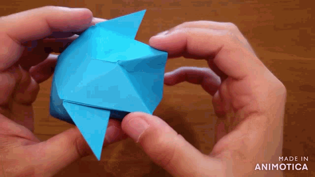 a person is holding a blue origami object that was made in animatica