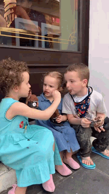a boy and two girls are eating ice cream in front of a window that says ' emily ' on it