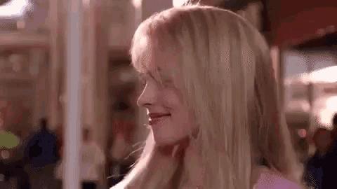 a close up of a woman 's face with blonde hair in a pink shirt .