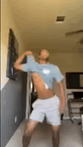 a shirtless man is dancing in a living room with his shirt off .
