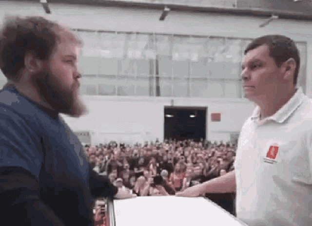 a man with a beard is standing next to another man in a white shirt