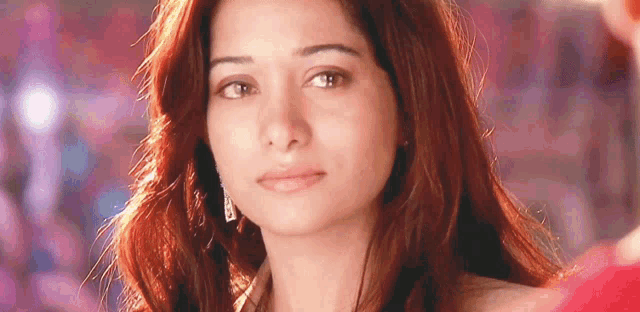 a close up of a woman 's face with long red hair and earrings