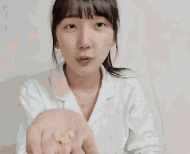 a woman wearing a white shirt and a necklace is making a funny face