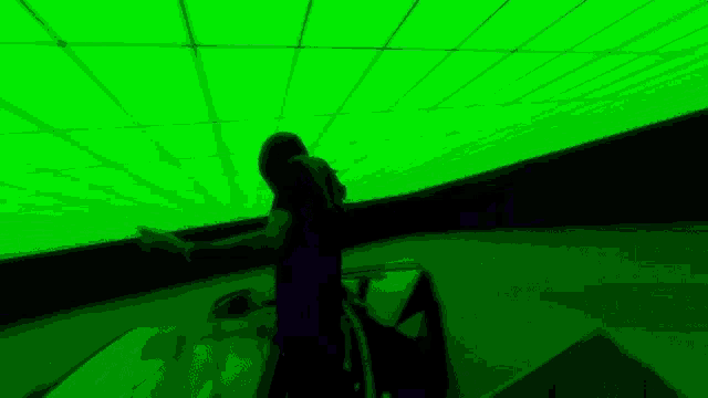a woman in a red dress is dancing in front of a green light .