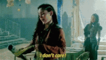 a woman is standing in a room and says `` i don 't care '' while another woman stands behind her .
