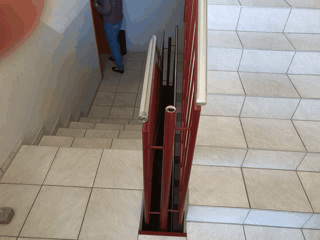 a red railing on a set of stairs with a man standing behind it