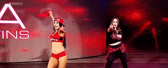 two female wrestlers are dancing on a stage in front of a large screen .