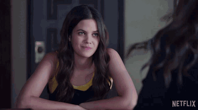 a woman sitting at a table with a netflix logo in the background