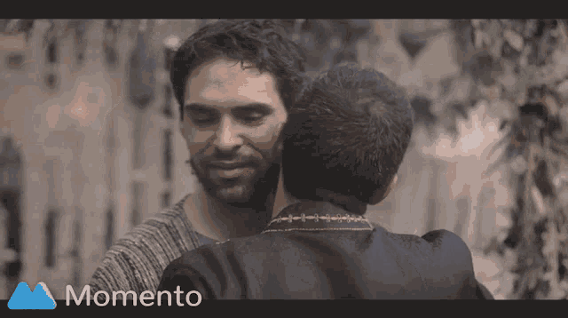 two men are hugging in a momento advertisement