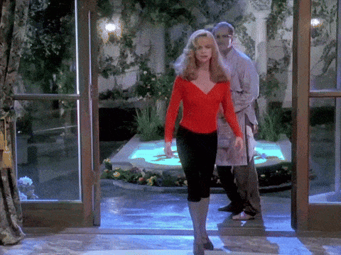 a woman in a red top and black pants stands in front of a glass door