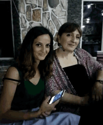 two women are sitting next to each other one is holding a cell phone