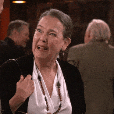 a woman wearing a black cardigan and a white shirt is making a face