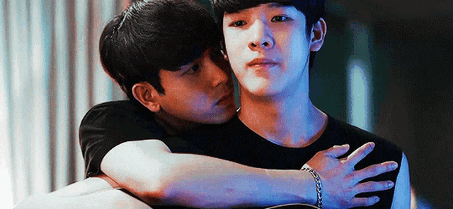 two young men are hugging each other and one of them is wearing a bracelet .