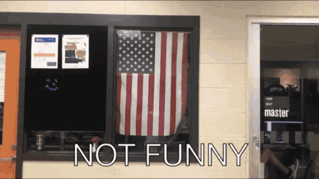 an american flag hangs in a window with the words not funny above it