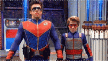two men in superhero costumes are standing next to each other in front of a building