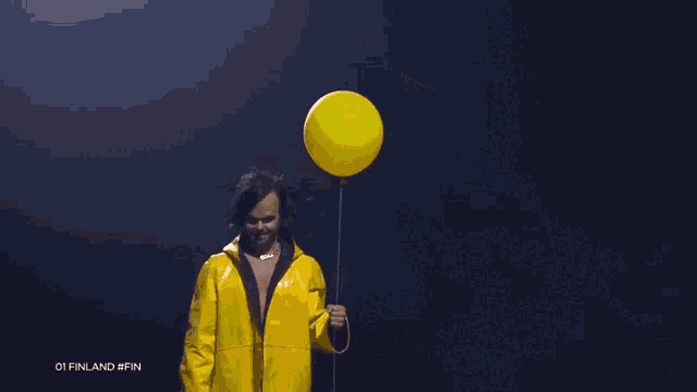 a man in a yellow raincoat is holding a yellow balloon in his hand