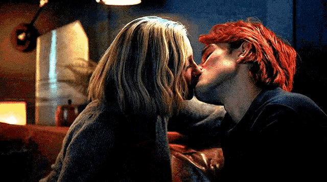 a man and woman are kissing on a couch .