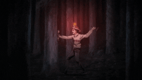 a man holding a flashlight in a dark forest with the letter j on his head