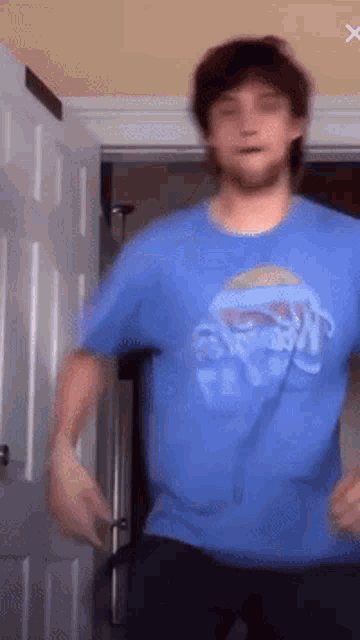 a man in a blue t-shirt is dancing in front of a door