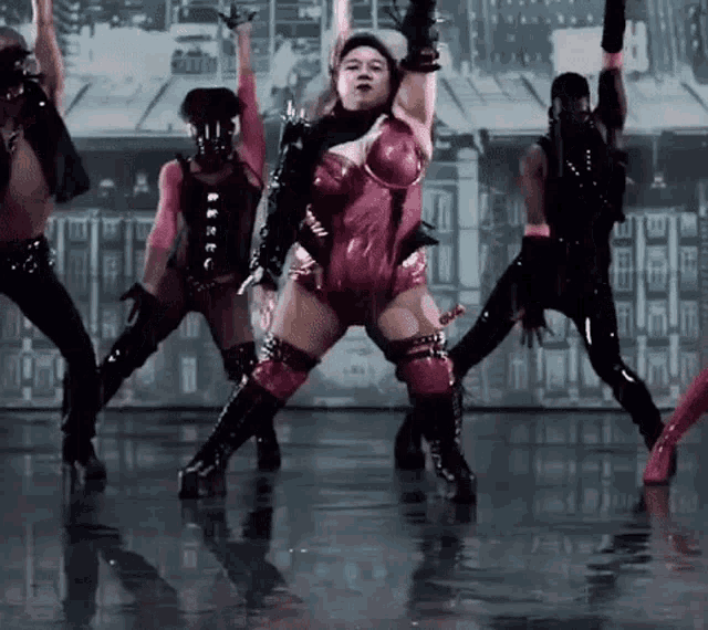 a woman in a pink bodysuit is dancing on a stage with other dancers