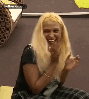 a woman with blonde hair is sitting on the floor with her hands in the air .