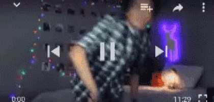 a man in a plaid shirt is dancing in a room with a purple light behind him .