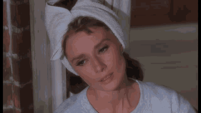 a woman with a towel wrapped around her head smiles