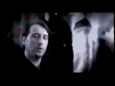 a man with his eyes closed is surrounded by other people