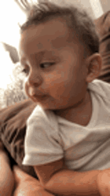 a baby in a white shirt is sitting on a couch .