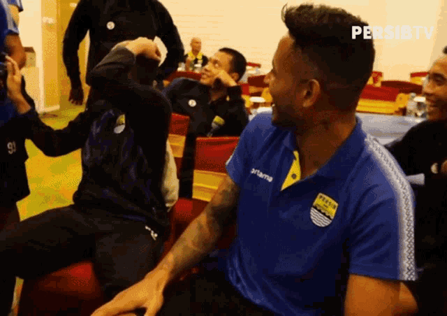 a man wearing a blue and yellow shirt that says persib on it