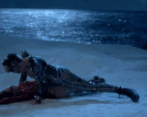 a man and woman are laying on the beach near the ocean