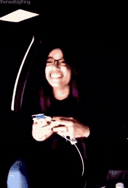 a woman wearing glasses is sitting in a car and laughing while holding a cell phone .