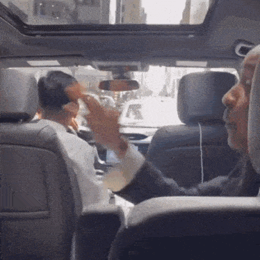 a man sitting in the back seat of a car talking on a phone
