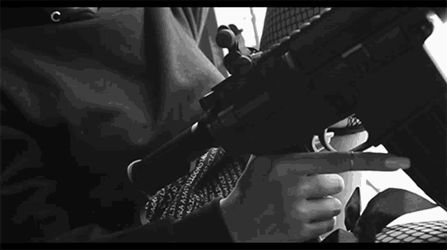 a black and white photo of a person holding a gun with the letter c on their shirt
