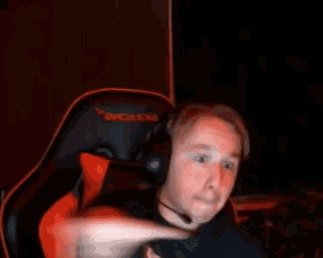 a man wearing headphones is sitting in a gaming chair and making a funny face .