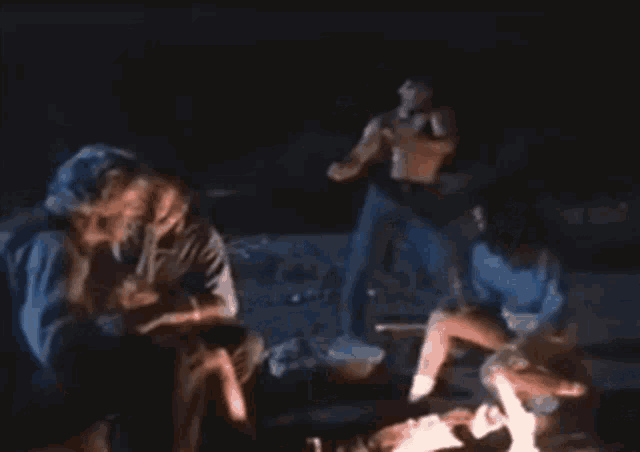 a group of people are gathered around a fire at night