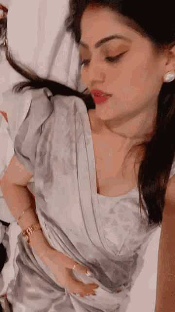 a woman laying on a bed taking a selfie with her hand on her stomach