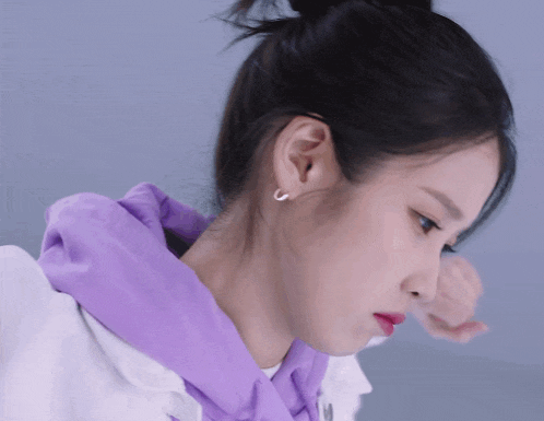 a close up of a woman wearing a purple hoodie and hoop earrings