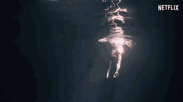a woman in a bathing suit is swimming in the dark with a netflix logo in the background