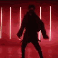 a silhouette of a man dancing in front of a red background with lights .