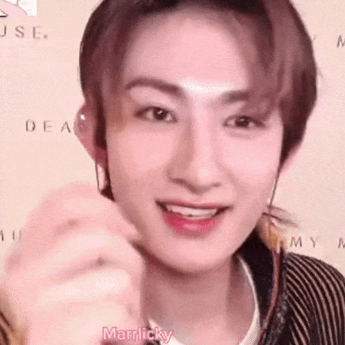 a close up of a young man wearing headphones and making a heart shape with his hands .