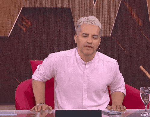 a man in a white shirt sits at a desk with his eyes closed