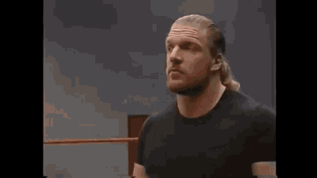 a man with long hair is standing in a wrestling ring .