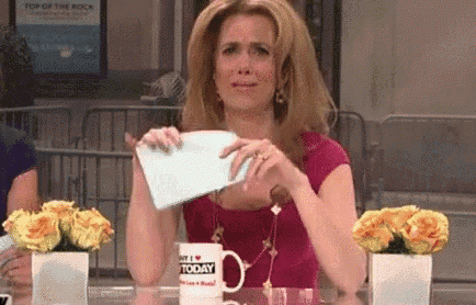 a woman is sitting at a table holding a piece of paper and a cup that says hello today .