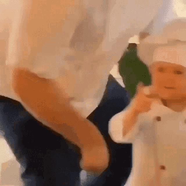 a man is holding a baby in a chef 's hat while dancing .
