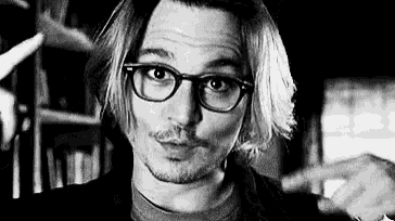 a man wearing glasses is pointing at something in a black and white photo .