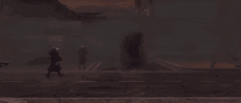 a man in a black coat is walking down a dark street