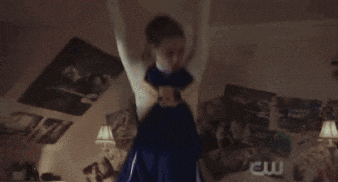 a cheerleader is standing in a room in front of a window .
